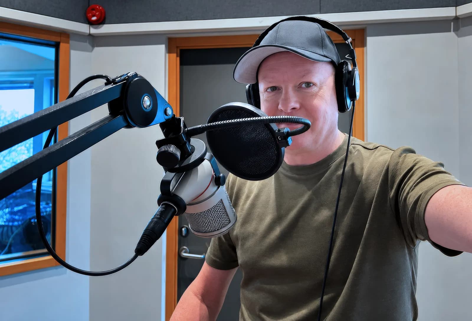 Rick med keps och hörlurar framför en studiomikrofon, inför radiointervjuerna 16 oktober 2026
